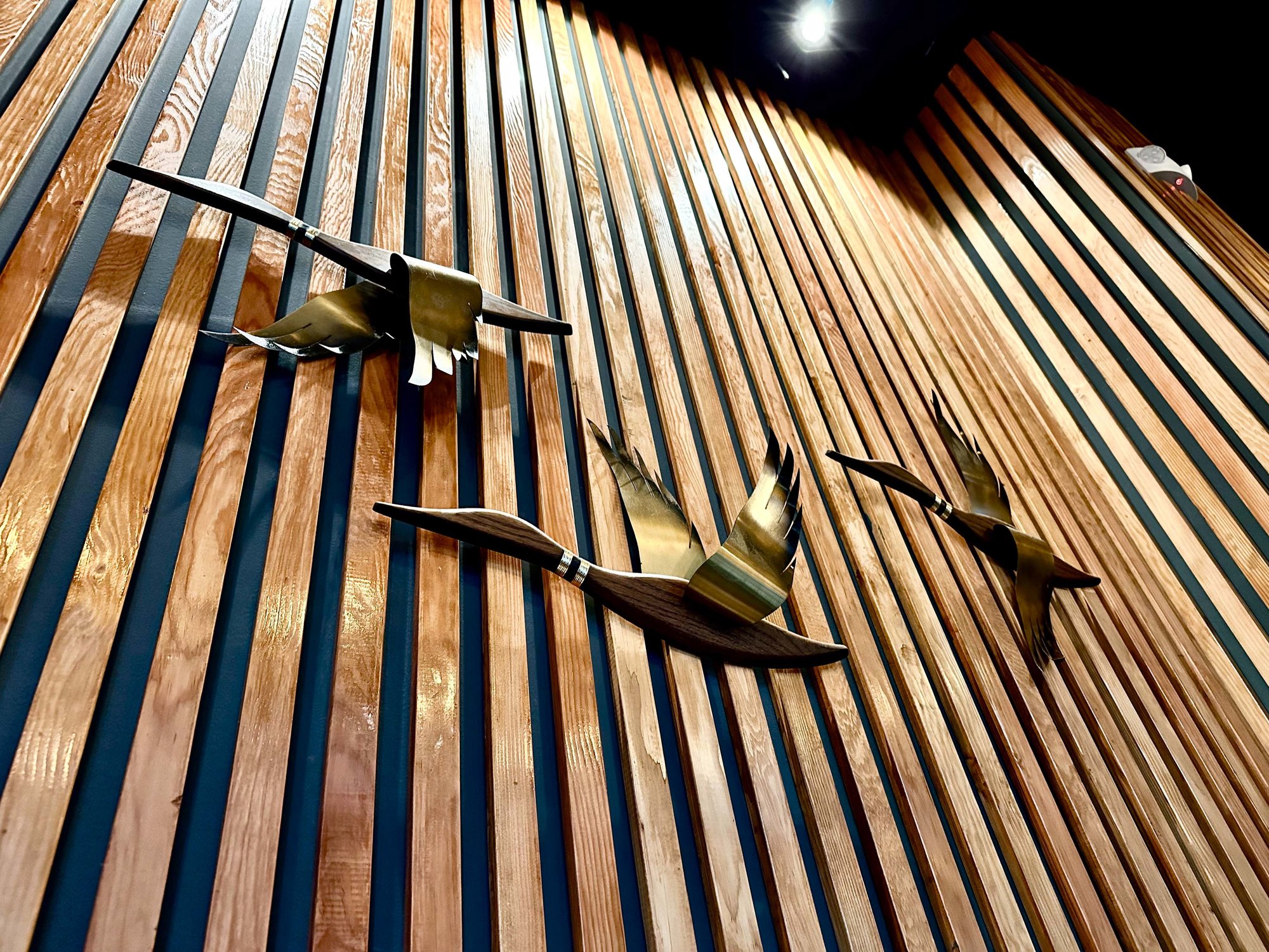 wood paneling on wall with metal ducks flying